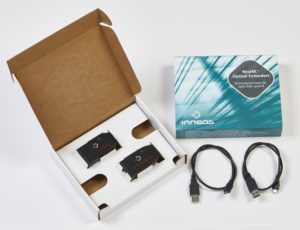 Inneos | Fiber Optic Components – Made in the USA An open cardboard box with a black extender resting inside with another box and black fiber cables next to it.