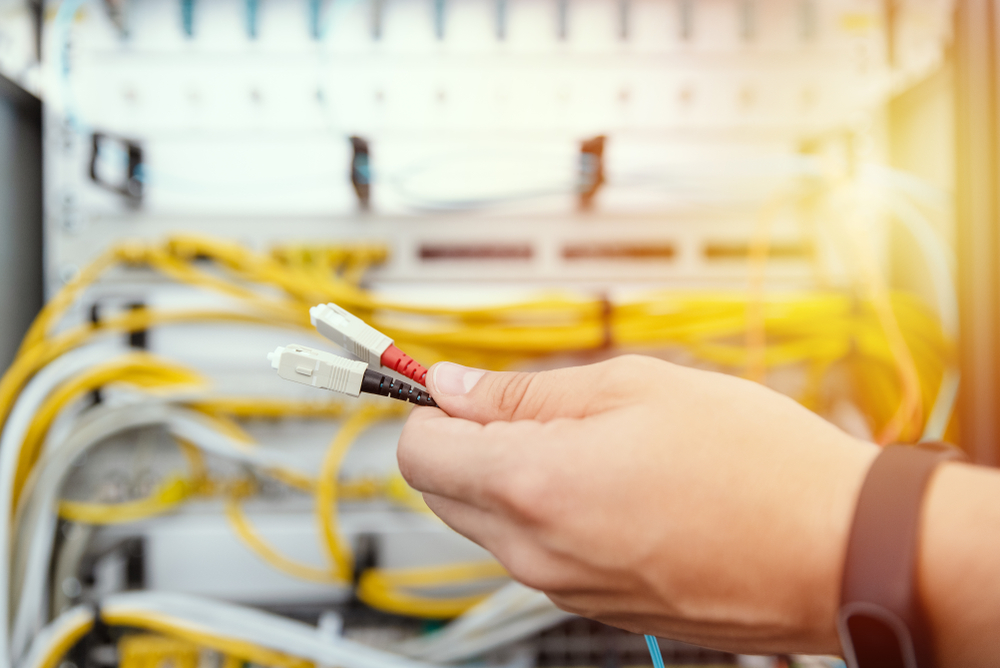 Inneos | What Is SWaP? A hand holding two fiber connectors and cables