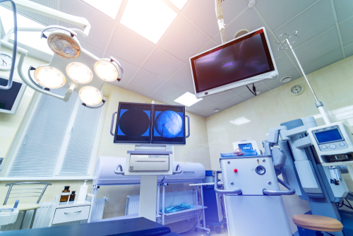 Two screens displaying medical video in a modern operating room.