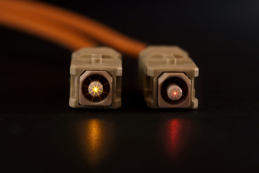 Inneos | Multimode vs. Single Mode Fiber: Does It Matter? Glowing fiber cable ends with SC connectors isolated on a black background.